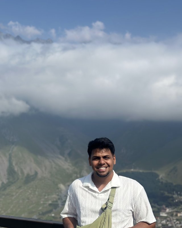 Ashwin at a mountain viewpoint with clouds below the peaks