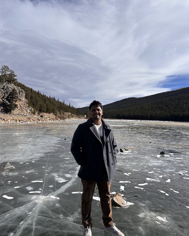 Ashwin standing on a frozen lake in the mountains